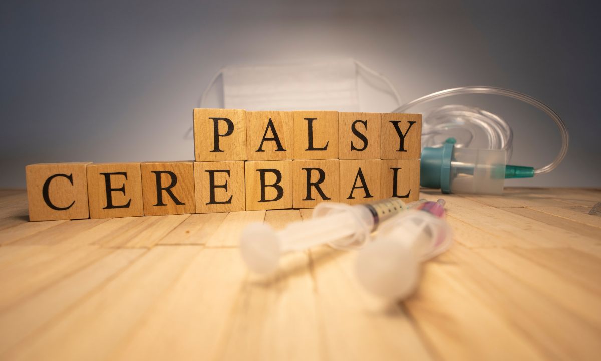 Blocks spelling cerebral palsy with medical tubes and syringes on a wooden table.