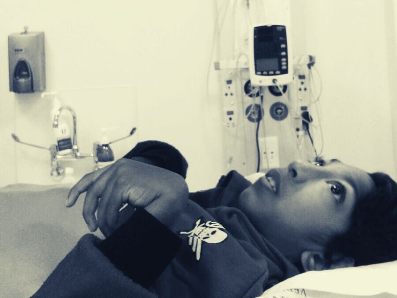 Jaden staring at the ceiling of a hospital room, with medical machines in a background.