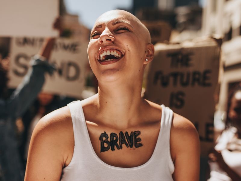 A lady laughing and being happy with the word brave painted across her chest.