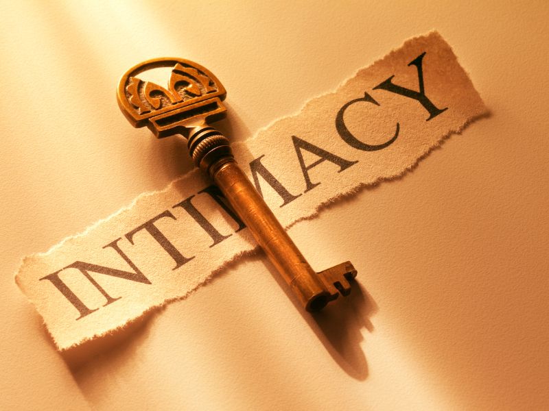 Image shows a torn piece of cream starched paper with the word intimacy in bold capital Italics and a bronze antique key placed on the paper over the ‘M’, all on a cream surface.