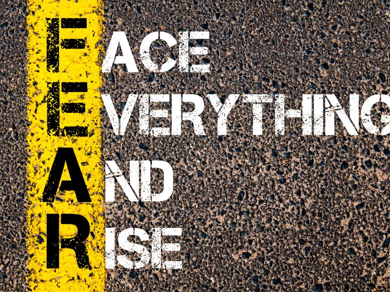 image shows words on a tar surface with black lettering in yellow saying FEAR and eleborated in white saying "face,everything and rise."