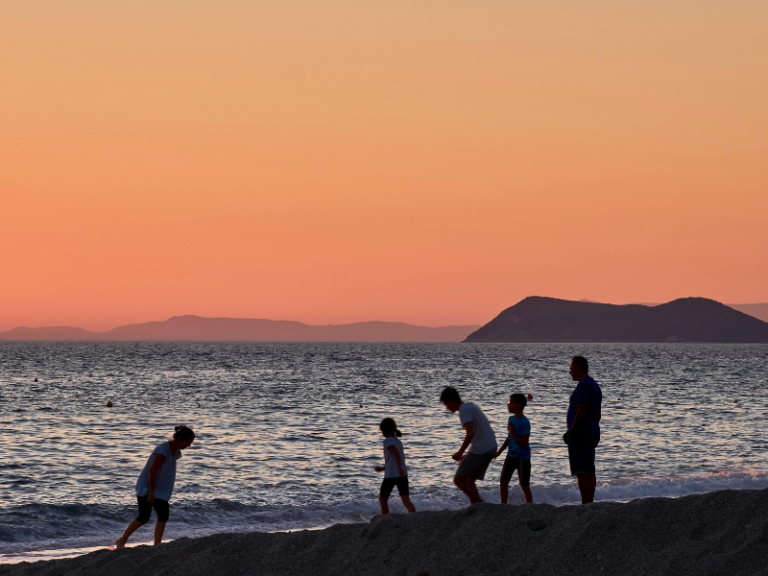 A Family silhouette at the beach while the sun sets