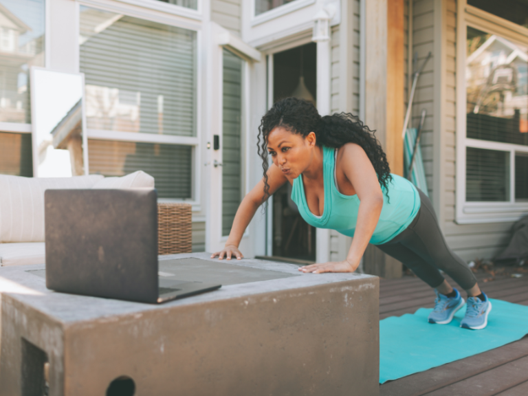 image shows a woman working out in the cmfort of her own home using online videos on her laptop